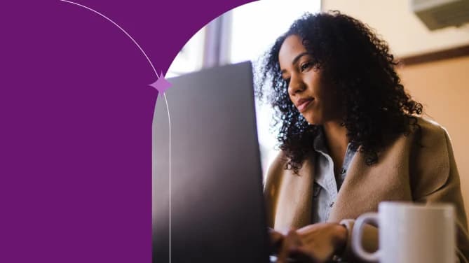 A person with long curly dark hair working on a laptop