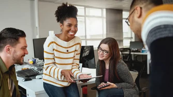 woman talking to her coworkers and showing them tablet