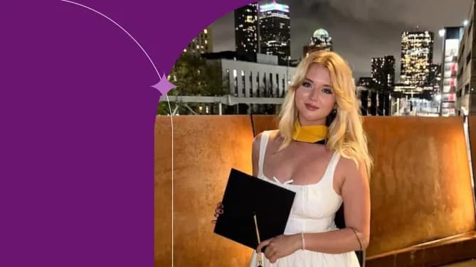 Cecelia D. in a white dress holding her graduation cap against the background of a city skyline. 